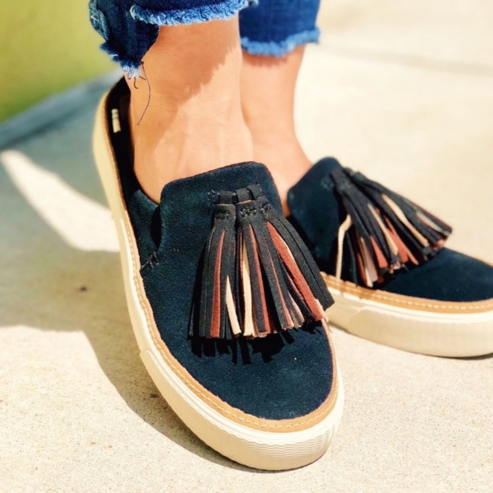 Toms Black slip ons or mules with tassel.